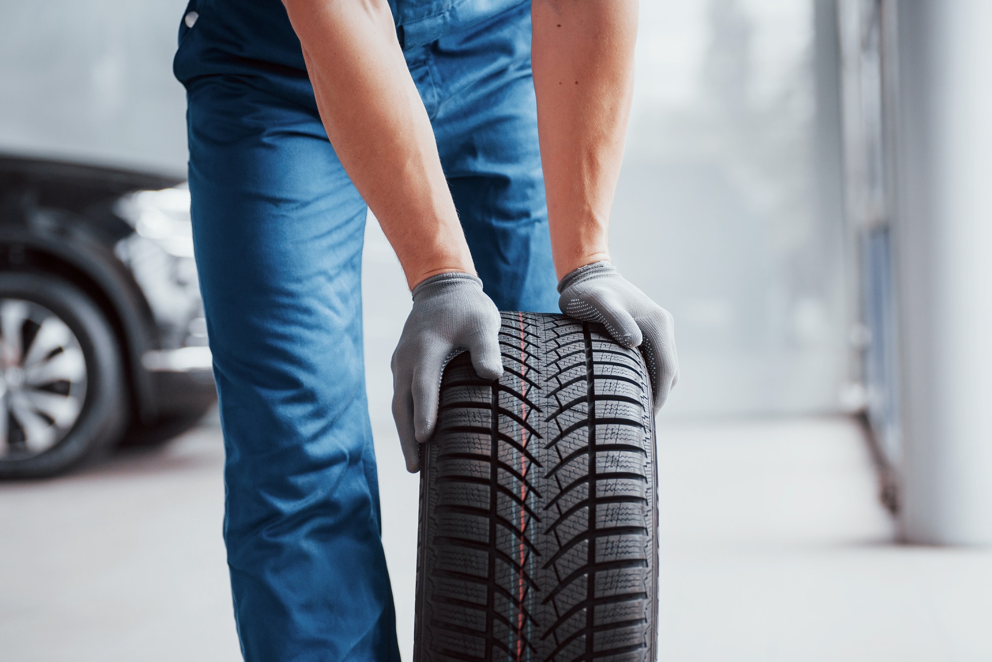 Mechanic holding a tire tire at the repair garage. replacement of winter and summer tires