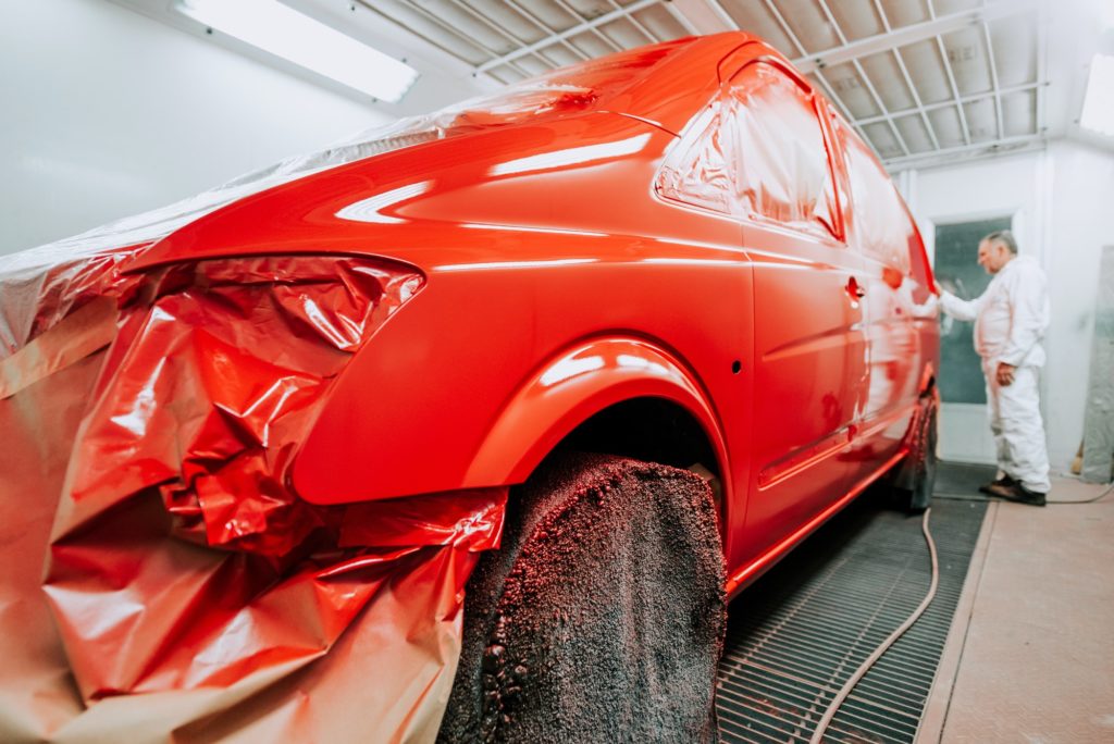 Details of worker inspecting new paint in car paint booth, preparing for laquer