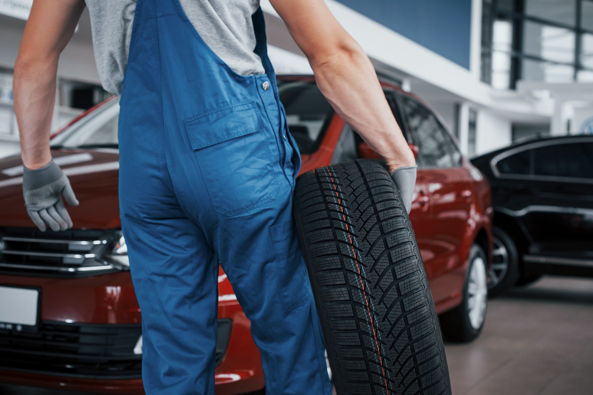 Mechanic holding a tire tire at the repair garage. replacement of winter and summer tires