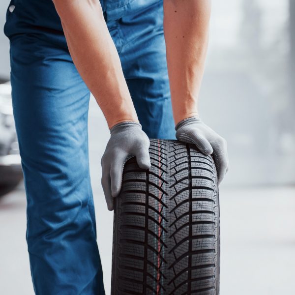 Mechanic holding a tire tire at the repair garage. replacement of winter and summer tires