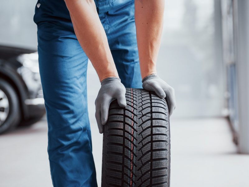 Mechanic holding a tire tire at the repair garage. replacement of winter and summer tires