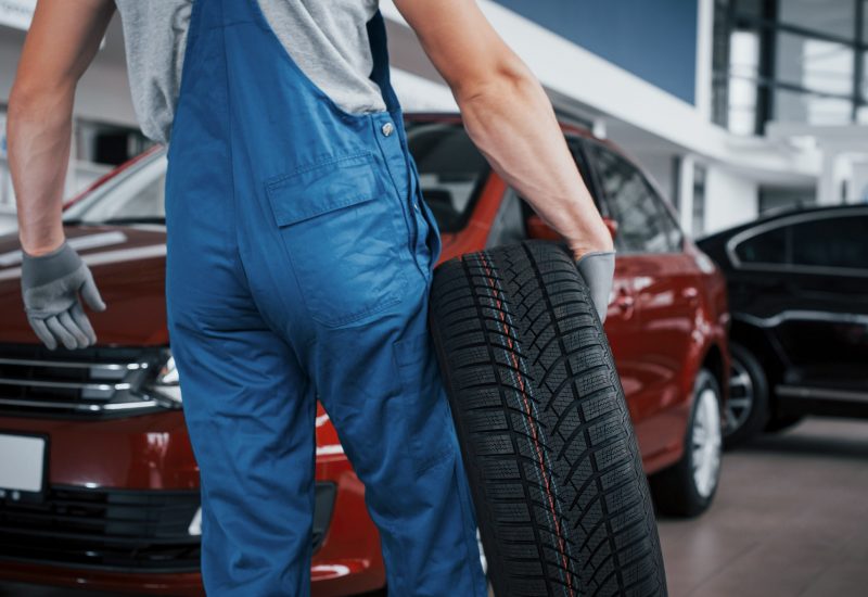 Mechanic holding a tire tire at the repair garage. replacement of winter and summer tires