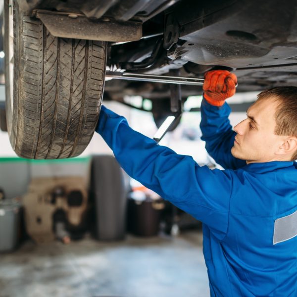 Mechanic repairs the suspension, car on the lift