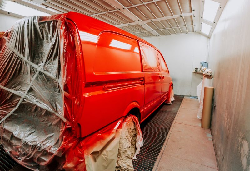 Red van in paint booth. Car workshop details, painting of a car