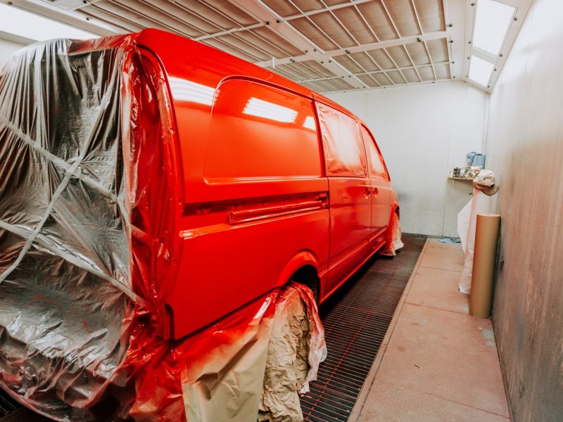 Red van in paint booth. Car workshop details, painting of a car